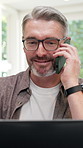 Freelance, phone call and happy man with laptop in home, publishing and communication with contact. Creative, remote work and mature person with mobile, laugh and chat for ebook publication in house