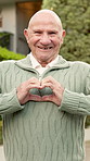 House, face and old man in front yard with heart hands, property purchase or wellness for retirement. Happy, senior person outdoor and moving in new home with love emoji, good mood and real estate.