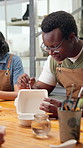 Man, relax and painting in art class with ceramics, learning DIY technique and creative expression. Artist, person and pottery creation in workshop with paintbrush, clay dish and tools for hobby.