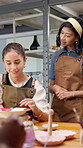 Teacher, people and painting in art studio with ceramics, explain design or guidance for technique. Instructor, women and teach in pottery workshop with paintbrush, discussion or tips for creativity.