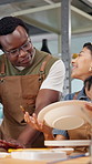 Instructor, people and painting in art class with clay bowl, explain design or advice for technique. Teacher, woman and man in ceramics workshop with paintbrush, discussion and tips for creativity.