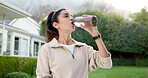 Drinking water, fitness and rest with woman in neighborhood for commitment or dedication to cardio. Exercise, happy and hydration with mature runner outdoor in residential backyard for health workout