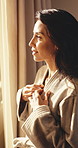 Woman, robe and thinking in hotel room with window, peaceful vacation and hospitality for wellness. Calm, mature person and cozy gown in lodge with reflection, self care and daydream for holiday.