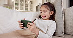 Girl, child and playing with phone on sofa in home for entertainment, online streaming or network. Kid, chatting or relaxing with smartphone for internet connection, gaming or subscription in house