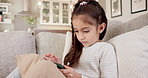 Girl, child or typing with phone on sofa in home for entertainment, online streaming or network. Kid, chatting or relaxing with smartphone for internet connection, gaming or app subscription in house