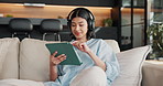 Woman, headphones and scroll in home with tablet, browsing social media and listen to music playlist. Happy, person and relax in lounge with audio tech, streaming radio and reading blog on website.