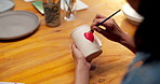 Ceramic, painting and hands with cup in&nbsp;workshop, creative and drawing heart shape with paintbrush. Pottery, craftsmanship and person with handmade mug, above and art process with equipment or color