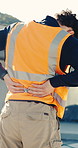 Worker, man and back pain on construction site with injury, building accident and massage for relief. Hurt, person and builder outdoor with muscle inflammation, fatigue and overworked from project.