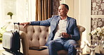 Businessman, waiting and coffee with suitcase in hotel for accommodation, hospitality or travel. Man, traveler or resident with luggage or drink on sofa for work trip, booking or business reservation