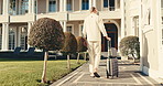 Back, man and arrival at hotel with luggage, check in and accommodation for holiday abroad. Thinking, mature person and walk outdoor with suitcase, guest service and resort entrance on vacation trip