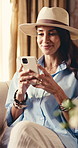 Phone, smile and woman in hotel lounge for digital check in, luxury hospitality or text on vacation. Mobile, happy mature person and relax for travel, deluxe accommodation and communication app