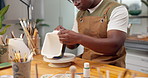 Pottery, hands and man painting ceramic in shop for merchandise, creative and small business. Black person, workshop and handmade craft store for manufacturing, productivity or artist process