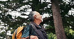 Senior, happy man and thinking in woods for hiking adventure, scenic break and explore nature. Fresh air, pensioner and trekking in forest with reflection, sightseeing and healthy aging with backpack