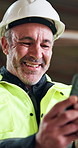 Man, engineer and phone at site for construction, schedule and safety survey for architecture. Smile, mature person and reading at workshop with mobile app, contact contractor and building approval
