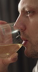Man, relax and drinking wine in home with reflection, wellness and stress free on calm weekend break. Happy, male person and thinking in living room with alcohol, chill and peaceful day in apartment.