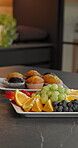 Breakfast, fruit and muffins on table, home and meal presentation on tray or wellness in kitchen. Brunch, nutrition and healthy food on counter, dessert and organic snacks with vitamin c in house