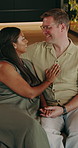 Couple, talk and holding hands at house with smile, love and romantic partner on valentines day. Happy, interracial people and relax in lounge with forehead kiss, romance and affection for commitment