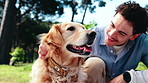 Happy, man and playing at park with dog, affection and loyal companion for animal interaction. Person, petting or embrace in nature with golden retriever, pet appreciation and foster care for bonding