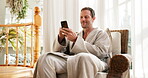 Spa, phone and mature man typing for hospitality rating, social media and check in at lodge. Happy person, technology and relax in reception area with mobile app, luxury accommodation and bathrobe