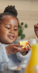 Smile, child and eating at house for breakfast, healthy fruit and vitamin c for balanced diet. Happy, family or toddler in kitchen with orange, organic snack and wellness lifestyle for brunch in home