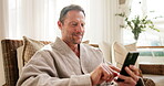 Phone, smile and mature man at wellness spa for hospitality rating, social media and check in. Happy person, technology and relax in waiting room with mobile app, luxury accommodation and bathrobe